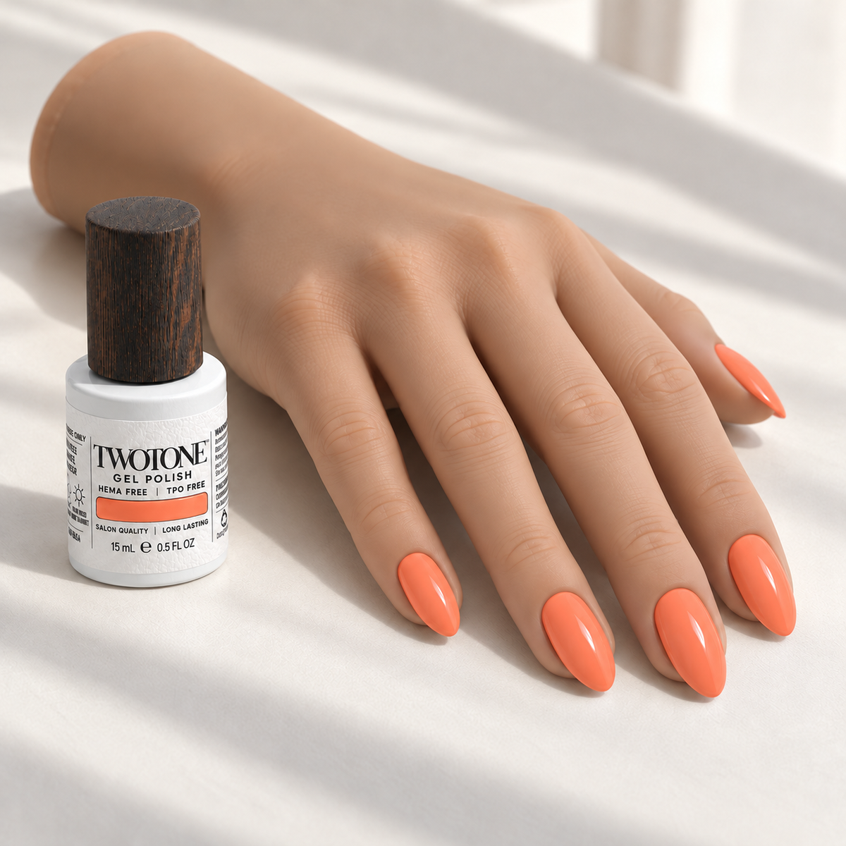 Illustrative Coral Whisper manicure on a silicone practice hand beside the TWOTONE bottle; color appearance may vary